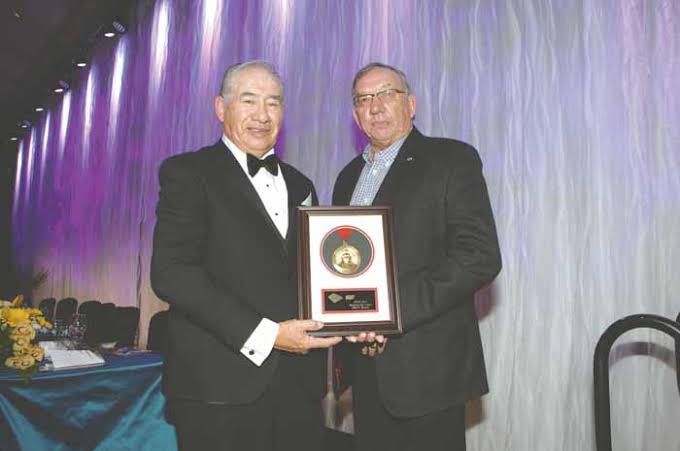 Sam Bosum receiving an award plaque